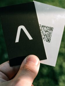 A person displaying a black and white business card featuring qr codes.