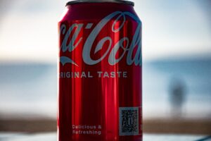 A can of coca cola with a QR code sits on a wooden table.