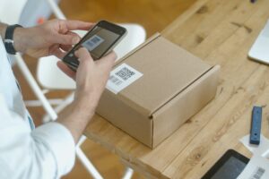 A man using a cell phone to scan a qr code on a box.