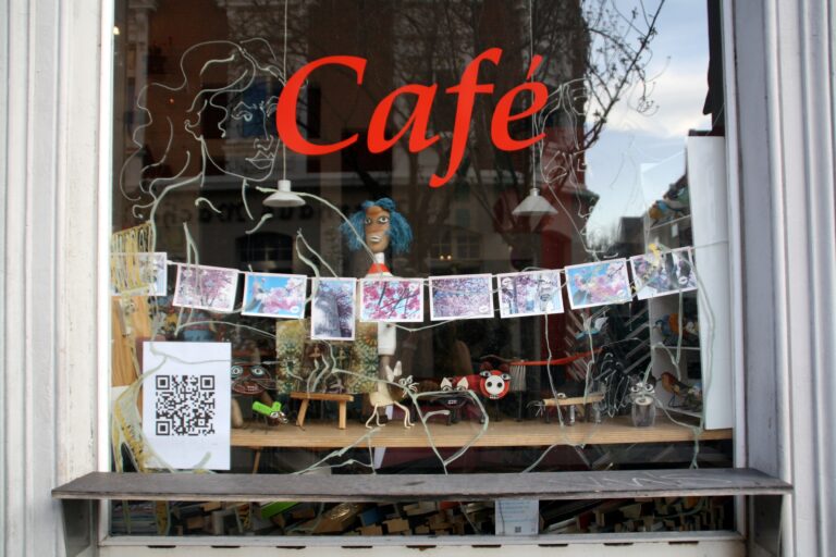 A window displaying a cafe sign featuring QR codes for small businesses.