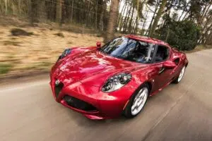 The red Alfa Romeo with smart features is driving down the road.